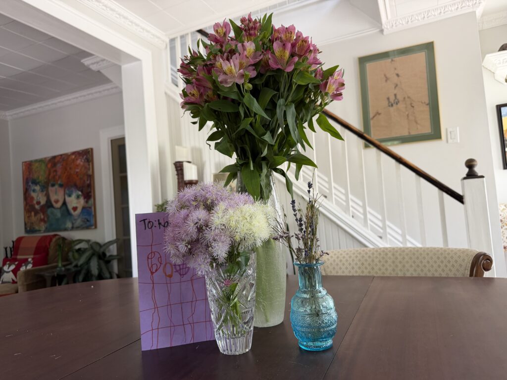 A photo demonstrating the somatic benefits of flowers through three specific floral gifts and a handmade card arranged on a table.